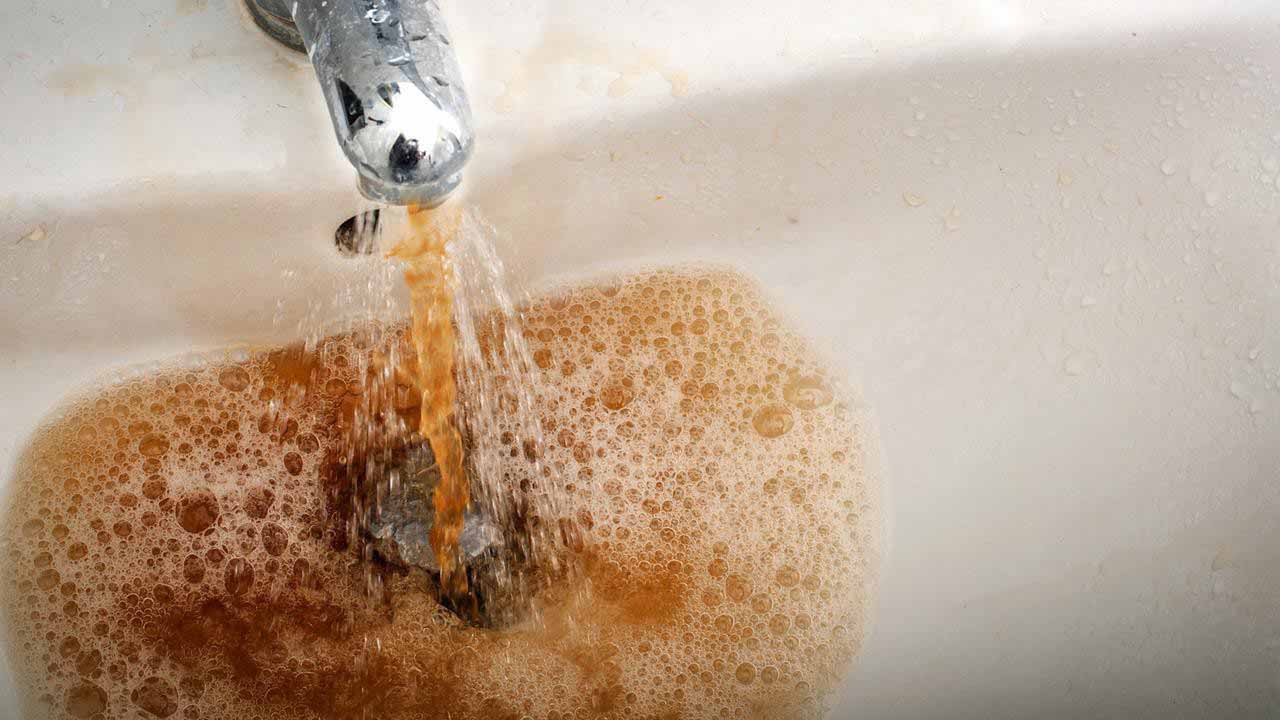 Image of dirty water coming out of a faucet.