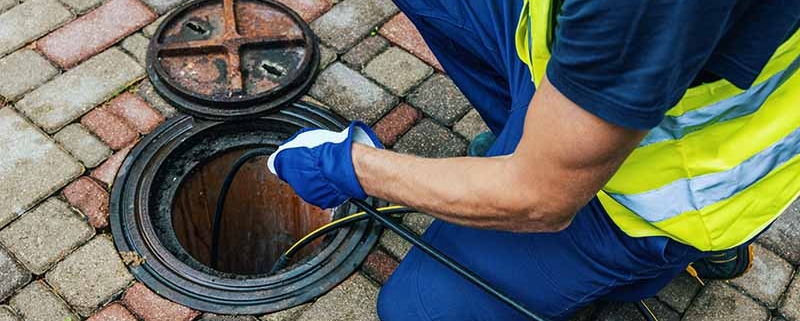 Closeup of a plumber performing a sewer line inspection to clear a blocked drain