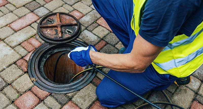 Closeup of a plumber performing a sewer line inspection to clear a blocked drain