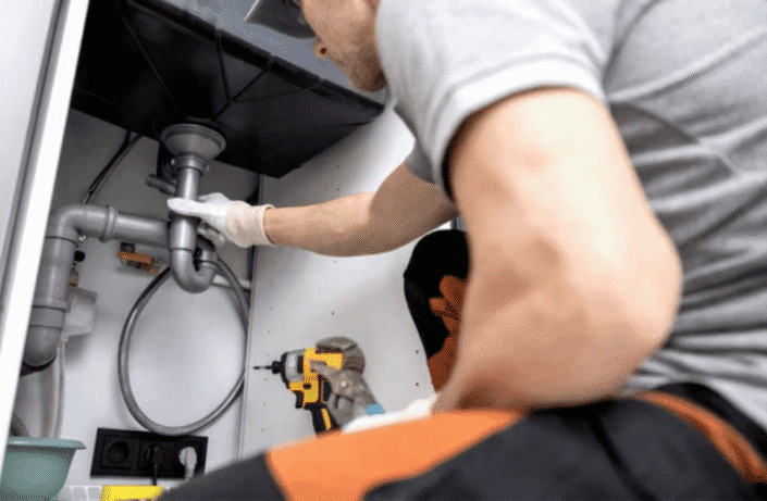 A professional plumber cleaning a clogged drain line using specialized tools.