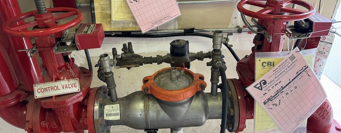 A licensed technician testing a commercial backflow preventer device at a business in Elgin, Illinois