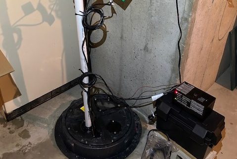 Licensed plumber installing a new submersible sump pump in an Elgin IL home basement