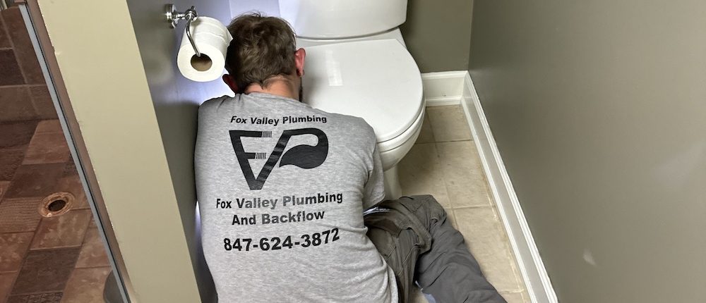 Licensed plumber performing toilet repair in Elgin IL bathroom