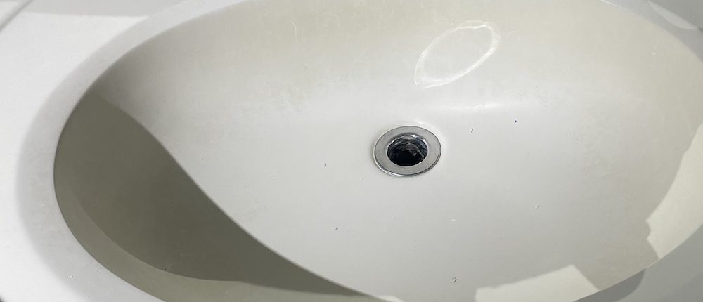Elgin homeowner inspecting bathroom sink plumbing under vanity