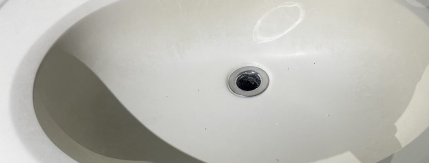 Elgin homeowner inspecting bathroom sink plumbing under vanity