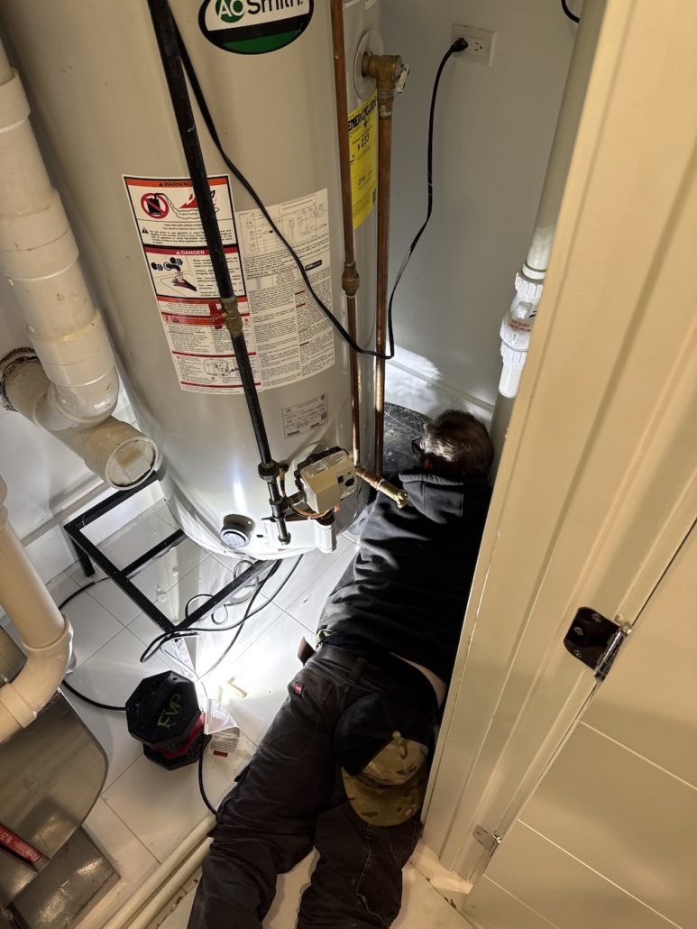 Licensed plumber performing a water heater inspection in an Elgin IL home